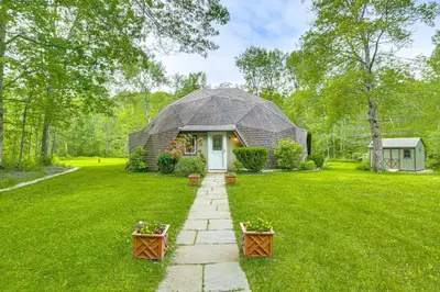 a barn style home with a stone path in the yard at Ski, Snowshoe and Fish Dome Escape in Nature! in Warren
