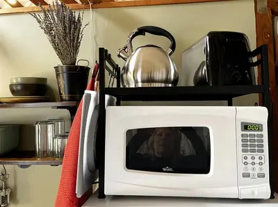 a woman is sitting on top of a microwave at Incredible Equipped Yurt Amazing for a Glamping Experience in East Meredith, New York in East Meredith