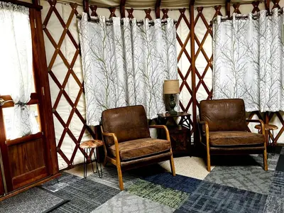 two chairs and a lamp in a room with curtains at Incredible Equipped Yurt Amazing for a Glamping Experience in East Meredith, New York in East Meredith