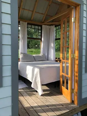 a bed on a porch of a house at Runamuk Farm Camp with a View near the Adirondacks in Cambridge