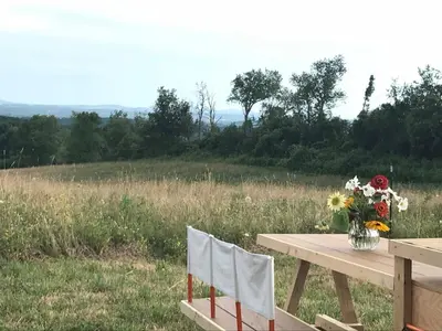 a wooden table with a vase of flowers on top of a field at Runamuk Farm Camp with a View near the Adirondacks in Cambridge