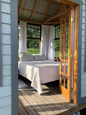 a bed on a porch of a house at Runamuk Farm Camp with a View near the Adirondacks in Cambridge
