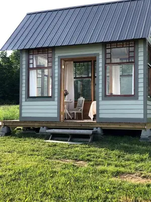 a small blue house with a table and a chair at Runamuk Farm Camp with a View near the Adirondacks in Cambridge