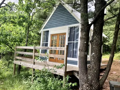a small house with a bench in front of a tree at Runamuk Farm Camp Tiny House near Cambridge, New York in Cambridge