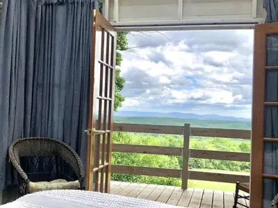 a bedroom with a door open to a balcony with a view at Runamuk Farm Camp Tiny House near Cambridge, New York in Cambridge