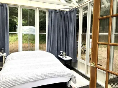 a bedroom with a bed and large windows at Runamuk Farm Camp Tiny House near Cambridge, New York in Cambridge