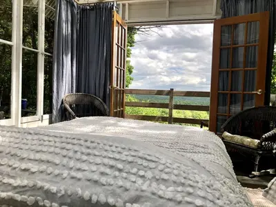 a bed on a porch with a view of the ocean at Runamuk Farm Camp Tiny House near Cambridge, New York in Cambridge