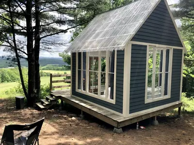 a small house with a roof and windows on a deck at Runamuk Farm Camp Tiny House near Cambridge, New York in Cambridge