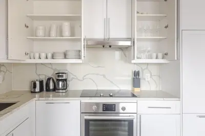 a kitchen with white cabinets and a stove at Blueground Bloomingdale fitness center nr Central Park NYC-1869 in New York