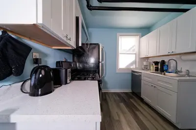 a kitchen with blue walls and white cabinets at Croton Nook - Cozy Getaway in Croton-on-Hudson