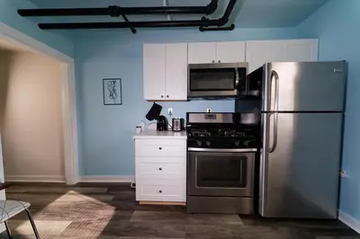 a kitchen with a stainless steel refrigerator and white cabinets at Croton Nook - Cozy Getaway in Croton-on-Hudson