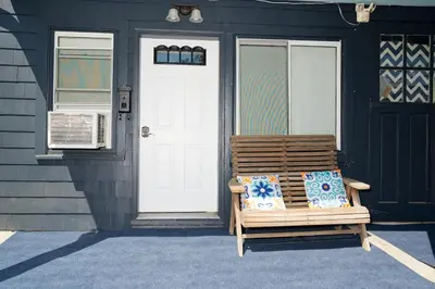 a wooden bench sitting outside of a house with a door at Croton Nook - Cozy Getaway in Croton-on-Hudson