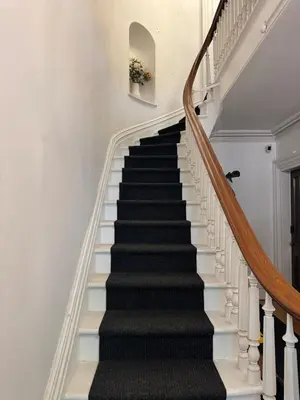 a staircase with black treads and white railings at Luxury Downtown w Backyard in Troy