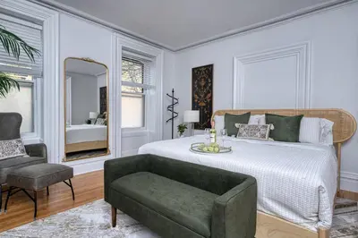 a bedroom with a bed and a chair and a mirror at Luxury Downtown w Backyard in Troy