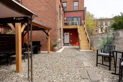 a patio with a table and chairs and a building at Luxury Downtown w Backyard in Troy