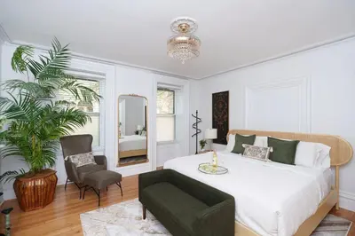 a bedroom with a bed and a chair and a mirror at Luxury Downtown w Backyard in Troy
