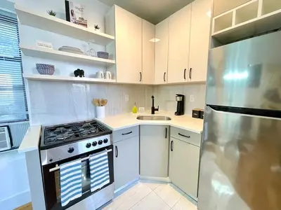 a kitchen with a stove and a stainless steel refrigerator at Madison Ave Oasis in New York