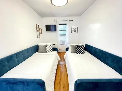 two beds in a room with a blue couch at Madison Ave Oasis in New York