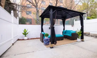 a black gazebo with blue chairs and plants at Lovely 1 bedroom apt with patio by Yankee Stadium in Melrose