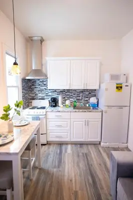 a kitchen with white cabinets and a white refrigerator at Lovely 1 bedroom apt with patio by Yankee Stadium in Melrose