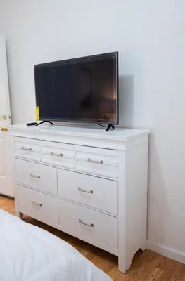 a white dresser with a flat screen tv on it at Lovely 1 bedroom apt with patio by Yankee Stadium in Melrose