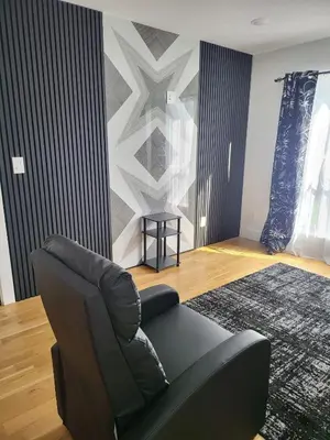 a living room with a black chair and a rug at Tkc Villa in Newark