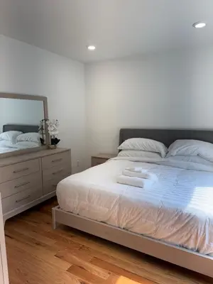 a bedroom with a white bed and a mirror at Elegant Retreat Near EWR n NYC in Newark