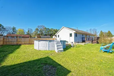a yard with a white house and a fence at Five-bedroom home in Schenectady