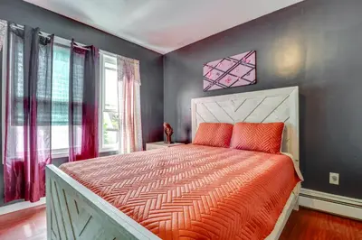 a bedroom with a bed with an orange comforter at 3 Mi to Dtwn Newark Eclectic and Walkable Apt! in Newark