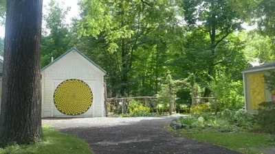 a white shed with a large yellow door in a yard at Morning Glory B n B Woodstock NY in Woodstock