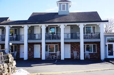 a building with white columns and tables and chairs at Stay Saratoga in Saratoga Springs