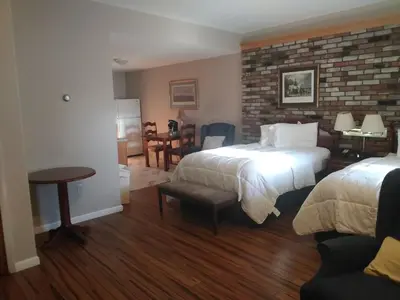 a hotel room with two beds and a brick wall at Stay Saratoga in Saratoga Springs