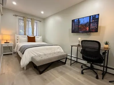 a bedroom with a bed and a chair and a television at Flushing City Escape in Flushing