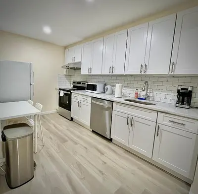 a kitchen with white cabinets and white appliances at Flushing City Escape in Flushing