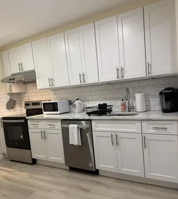 a kitchen with white cabinets and a stove top oven at Flushing City Escape in Flushing