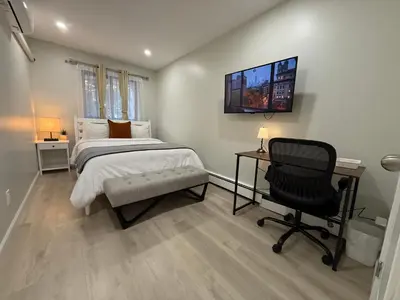 a bedroom with a bed and a desk and a chair at Flushing City Escape in Flushing