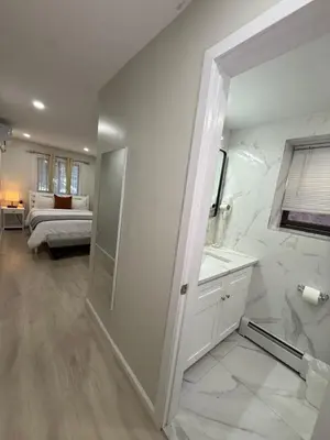 a bathroom with a shower and a sink and a bedroom at Flushing City Escape in Flushing