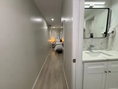 a white bathroom with a sink and a mirror at Flushing City Escape in Flushing