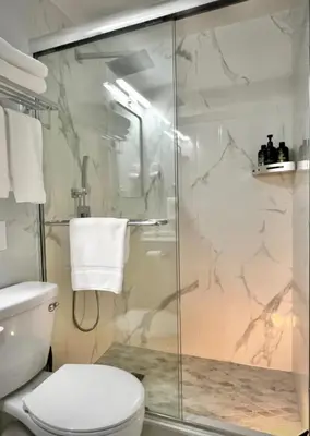 a bathroom with a toilet and a glass shower at Flushing City Escape in Flushing
