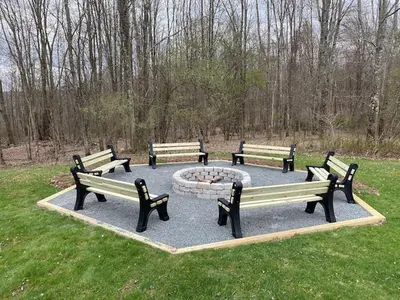 a group of park benches sitting around a fire pit at Nature's Retreat 4-Bedroom Cabin in Honesdale