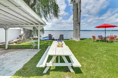 a picnic table on the grass next to the water at Private Dock Lakefront Gem on Saratoga Lake in Saratoga Springs