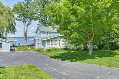 a blue house with a tree and a driveway at Private Dock Lakefront Gem on Saratoga Lake in Saratoga Springs