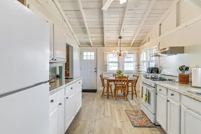 a kitchen with white cabinets and a table with chairs at Private Dock Lakefront Gem on Saratoga Lake in Saratoga Springs