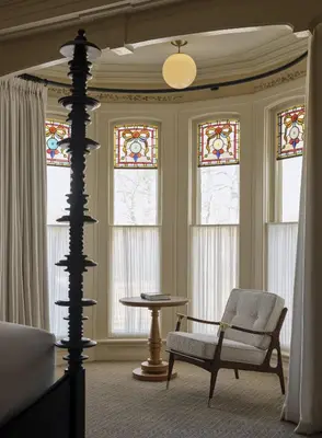 a living room with a chair and stained glass windows at Belden House & Mews in Litchfield