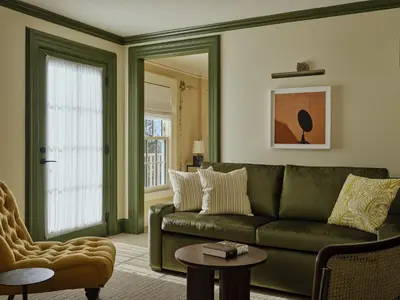 a living room with a green couch and a chair at Belden House & Mews in Litchfield
