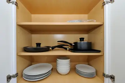 a cupboard with plates and pots and pans and plates at Cozy Studio Near Central Park in New York