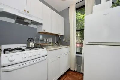 a white kitchen with a stove and a refrigerator at Cozy Studio Near Central Park in New York