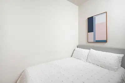 a bed in a bedroom with a painting on the wall at Beautiful 3 Bedroom Unit in Prime Location in New York