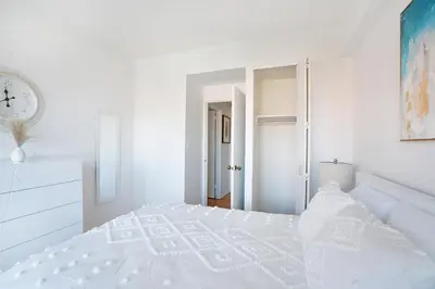 a white bedroom with a white bed and a clock at Sunny 3 BR 1 Bath Apartment in NYC in New York