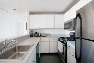 a white kitchen with a sink and a refrigerator at Sunny 3 BR 1 Bath Apartment in NYC in New York